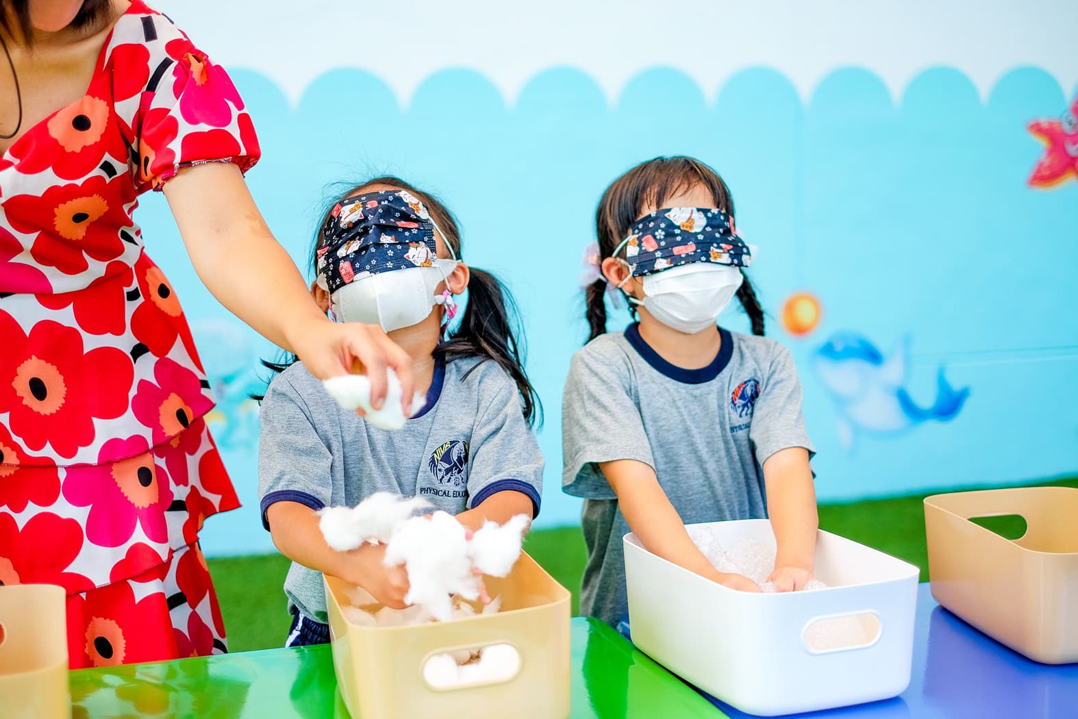 NIVA kindergarten students engaging in play-based learning, using their sense of touch to determine the object their holding.