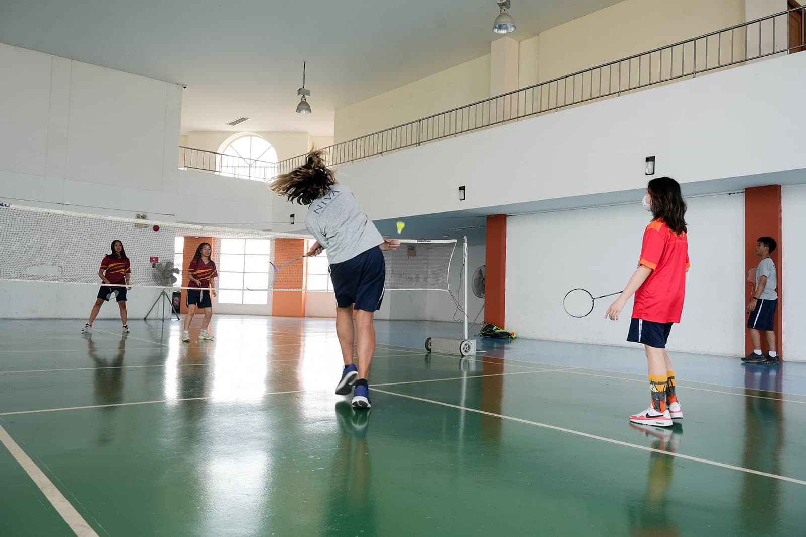 A NIVA student smashing in a badminton game with her friends