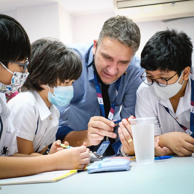 A NIVA teacher teaching three boys.