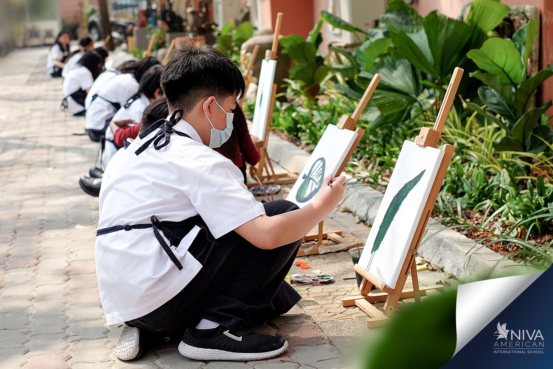 นักเรียนวาดภาพใบไม้ข้างสวนในลานโรงเรียน