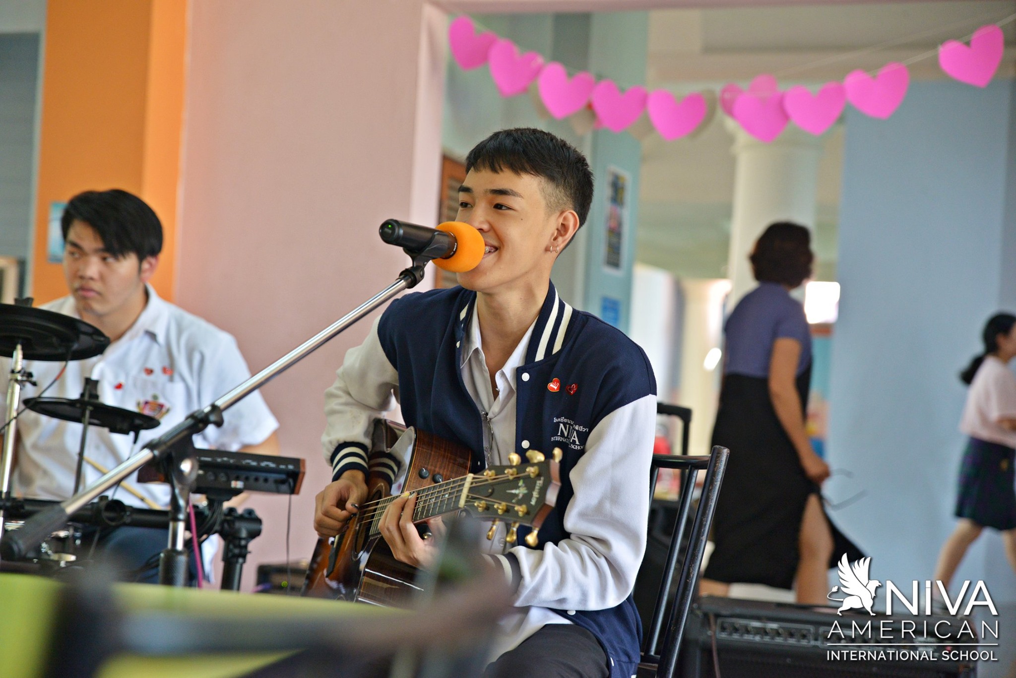 Student singing and playing guitar at a microphone