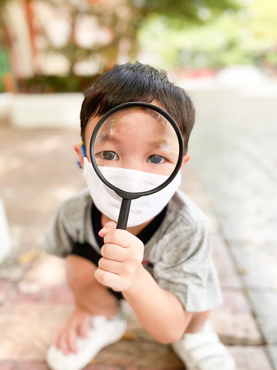 Kindergarten child looking through a magnifying glass