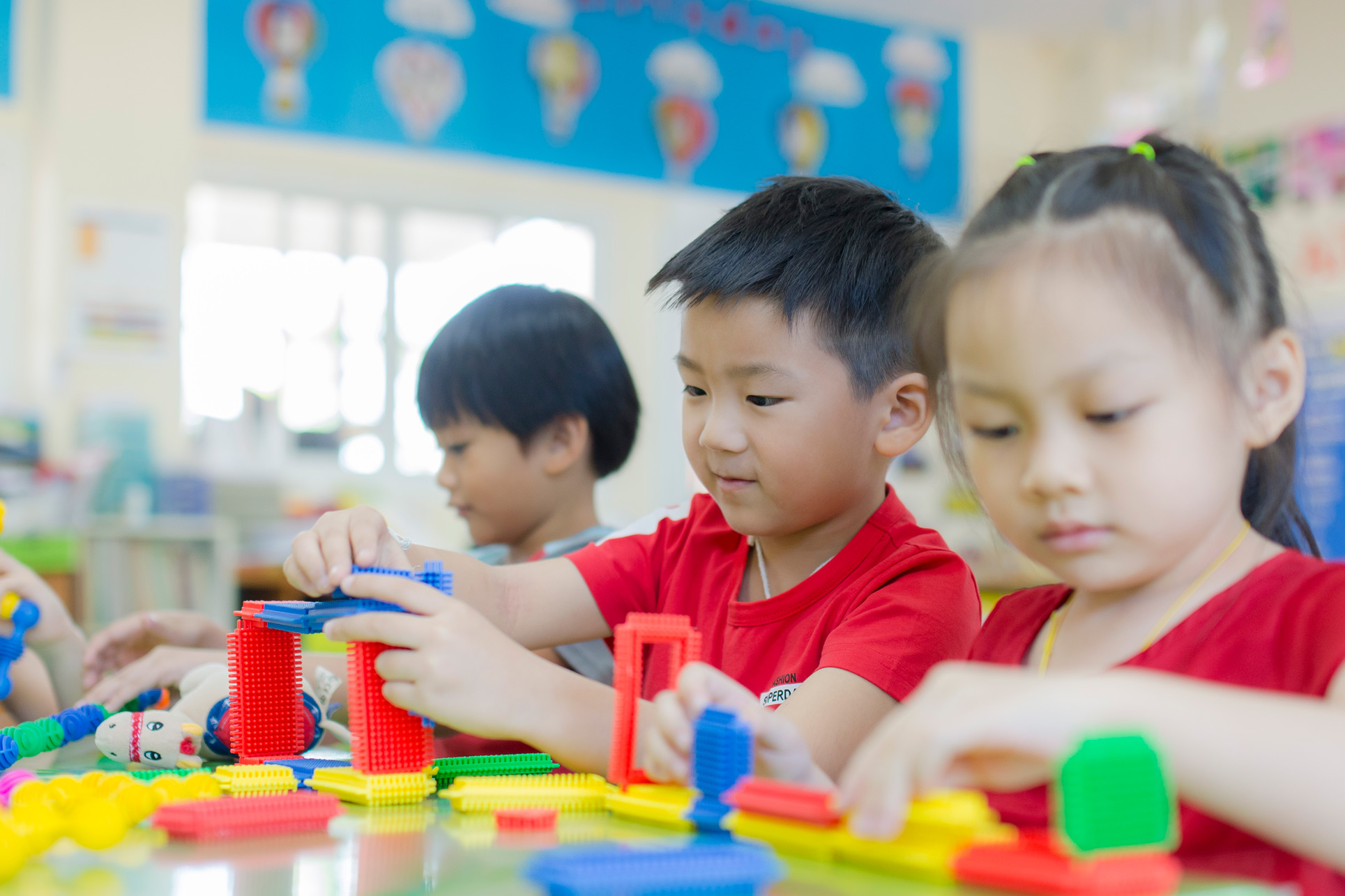 Kindergarten students building with colorful blocks