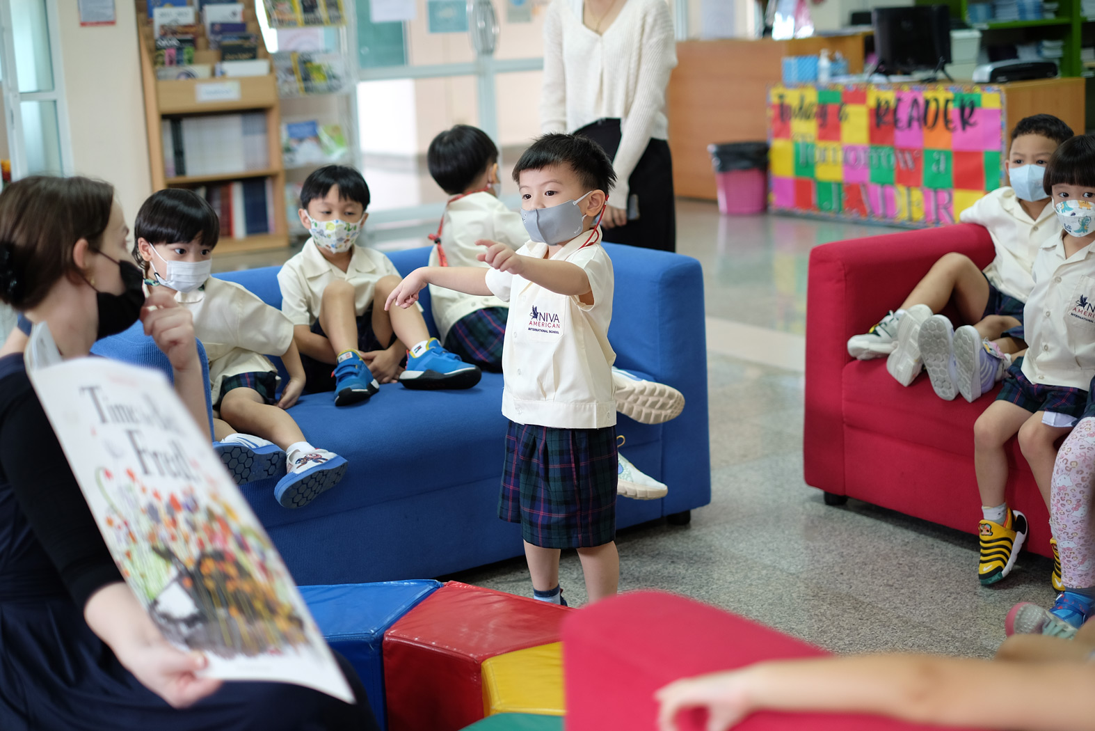 นักเรียนอนุบาลแสดงหนังสือให้เพื่อนดูในห้องสมุด