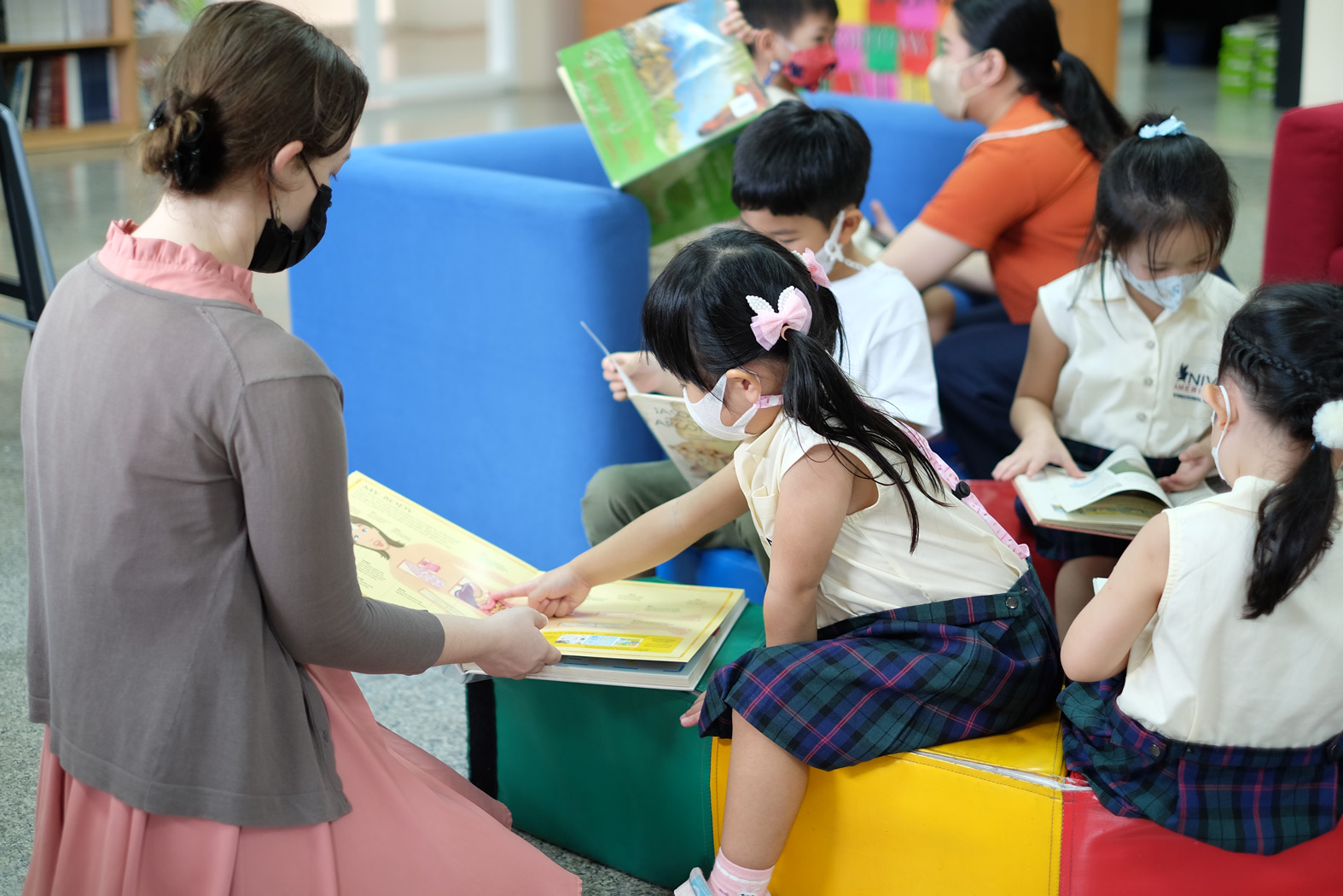 ครูอ่านหนังสือกับนักเรียนอนุบาลในห้องสมุด