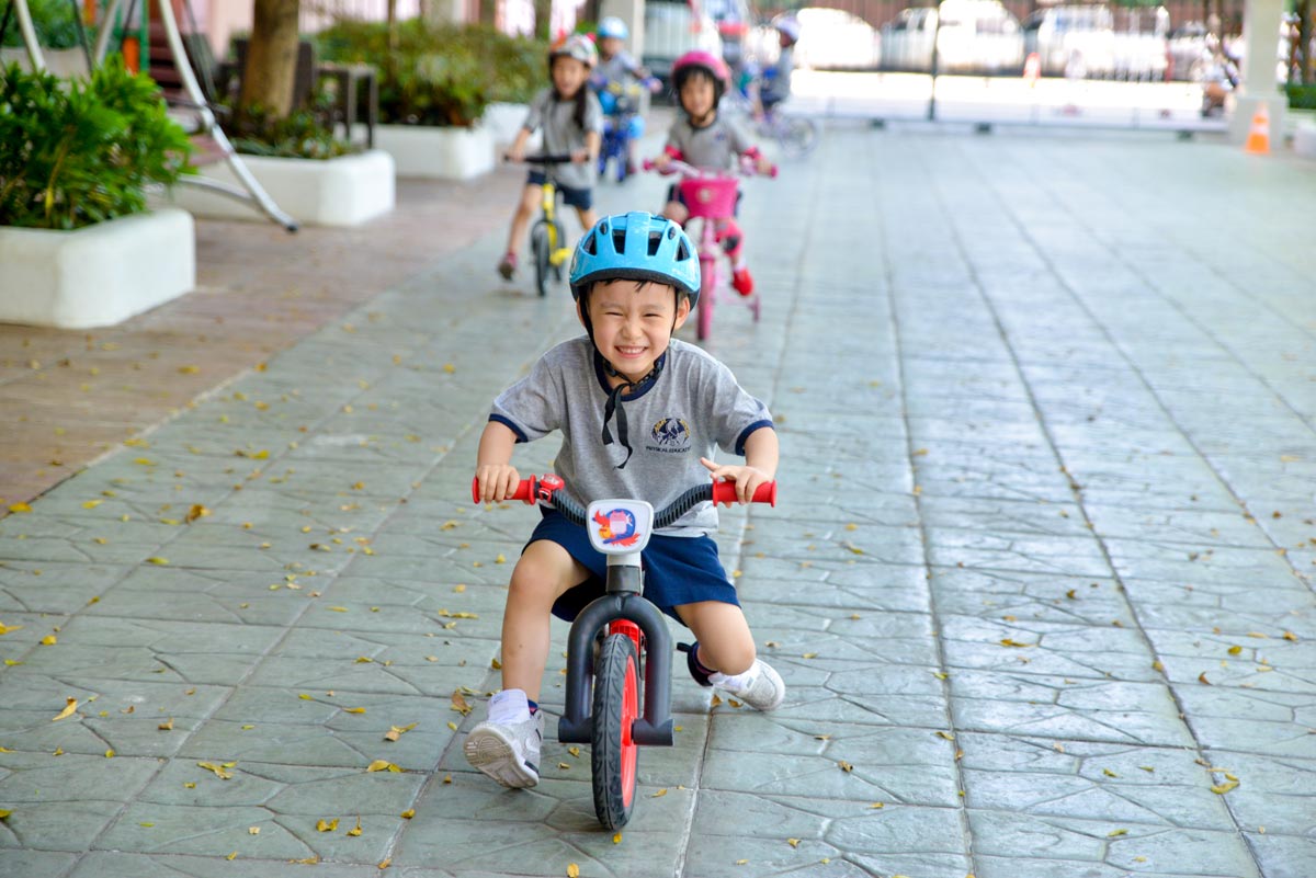Kindergarten students riding bicycles in the patio