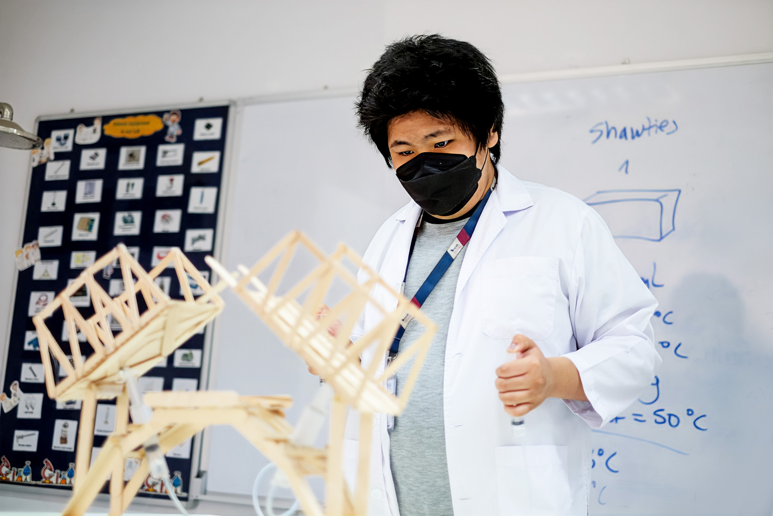 Student holding a miniature wooden bridge in the science lab
