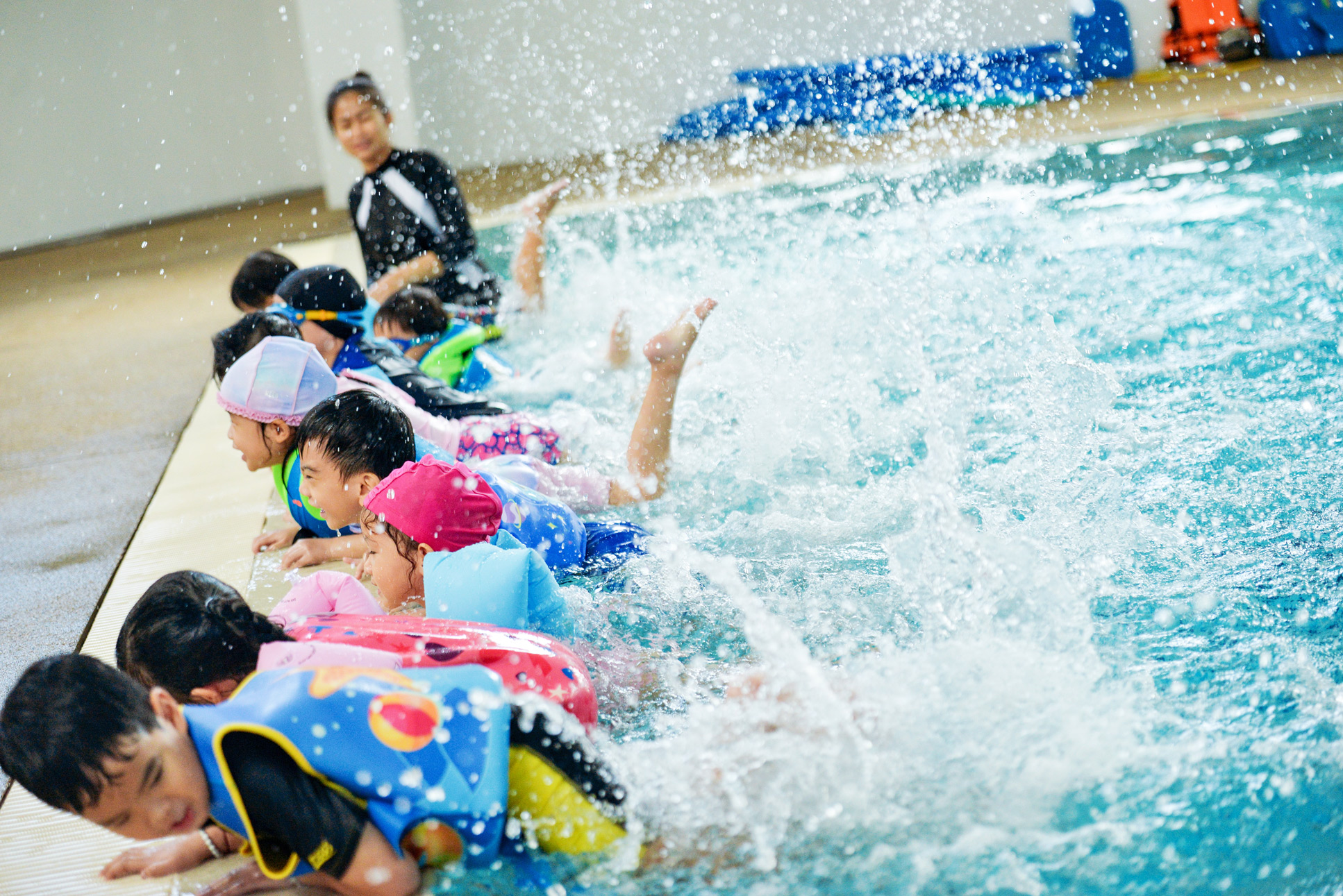 Students practicing kicks at the edge of the swimming pool