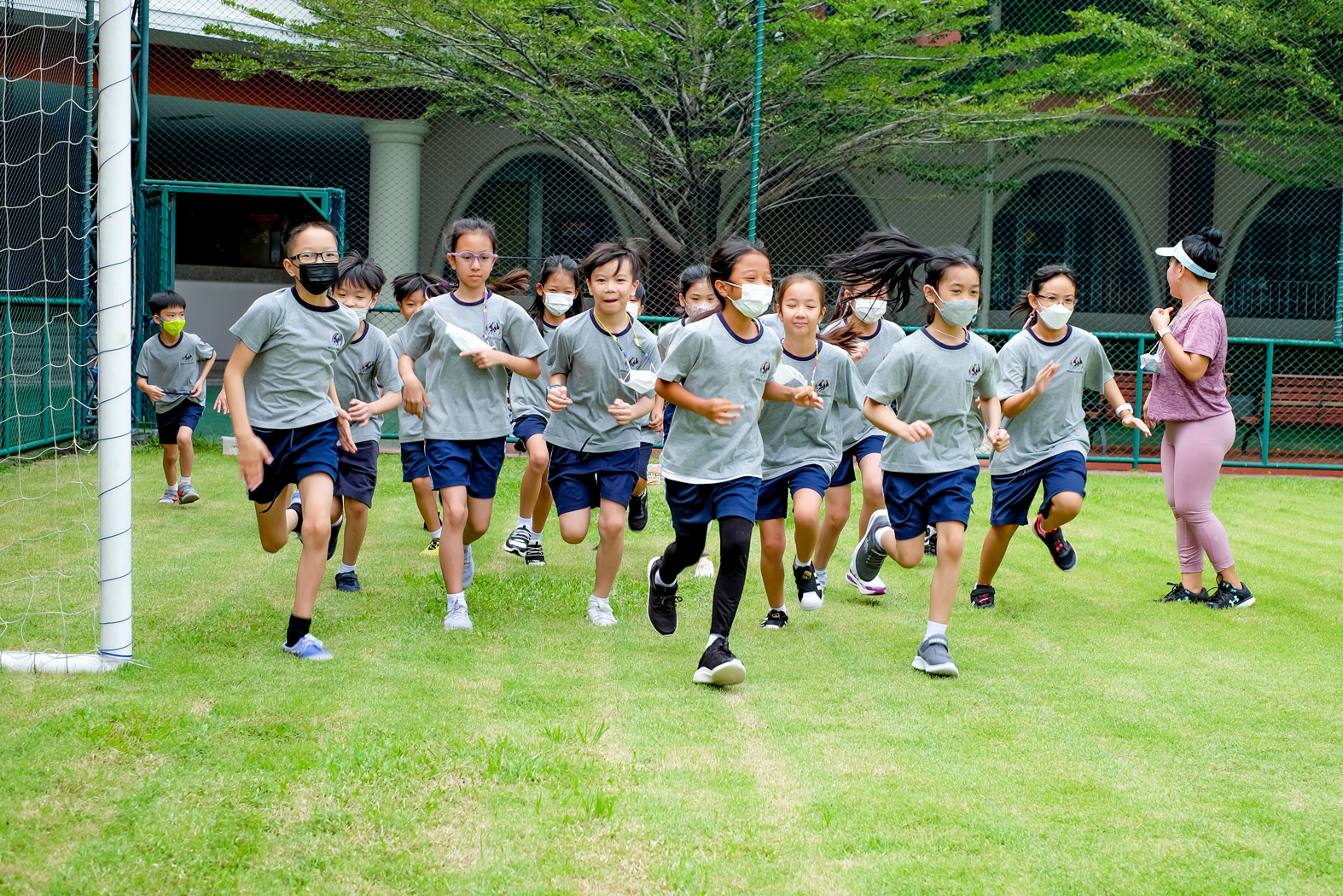 นักเรียนวิ่งด้วยกันในวิชาพลศึกษาบนสนามหญ้า