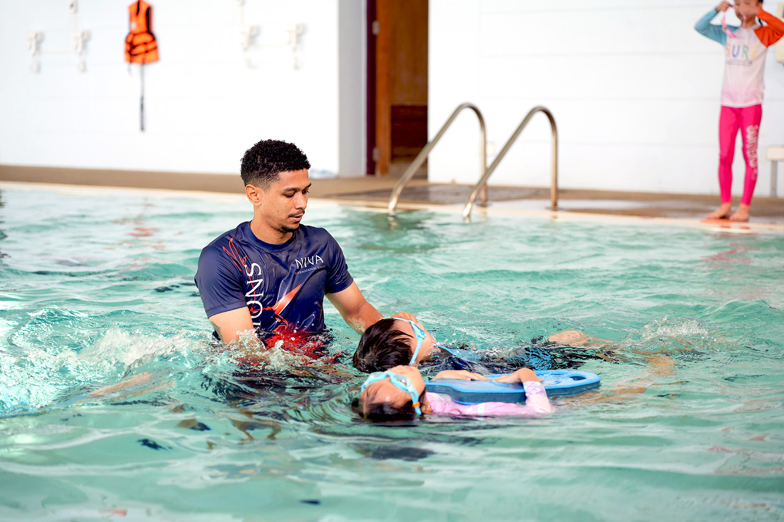 Swimming instructor supporting a student using a float