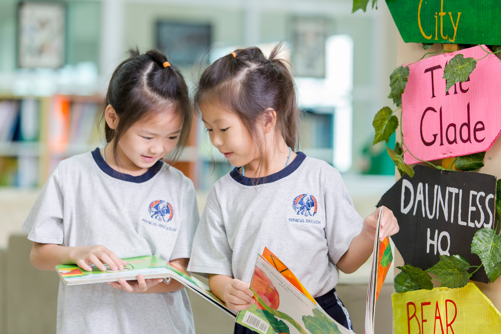 นักเรียนหญิงสองคนอ่านหนังสือด้วยกันในห้องสมุด