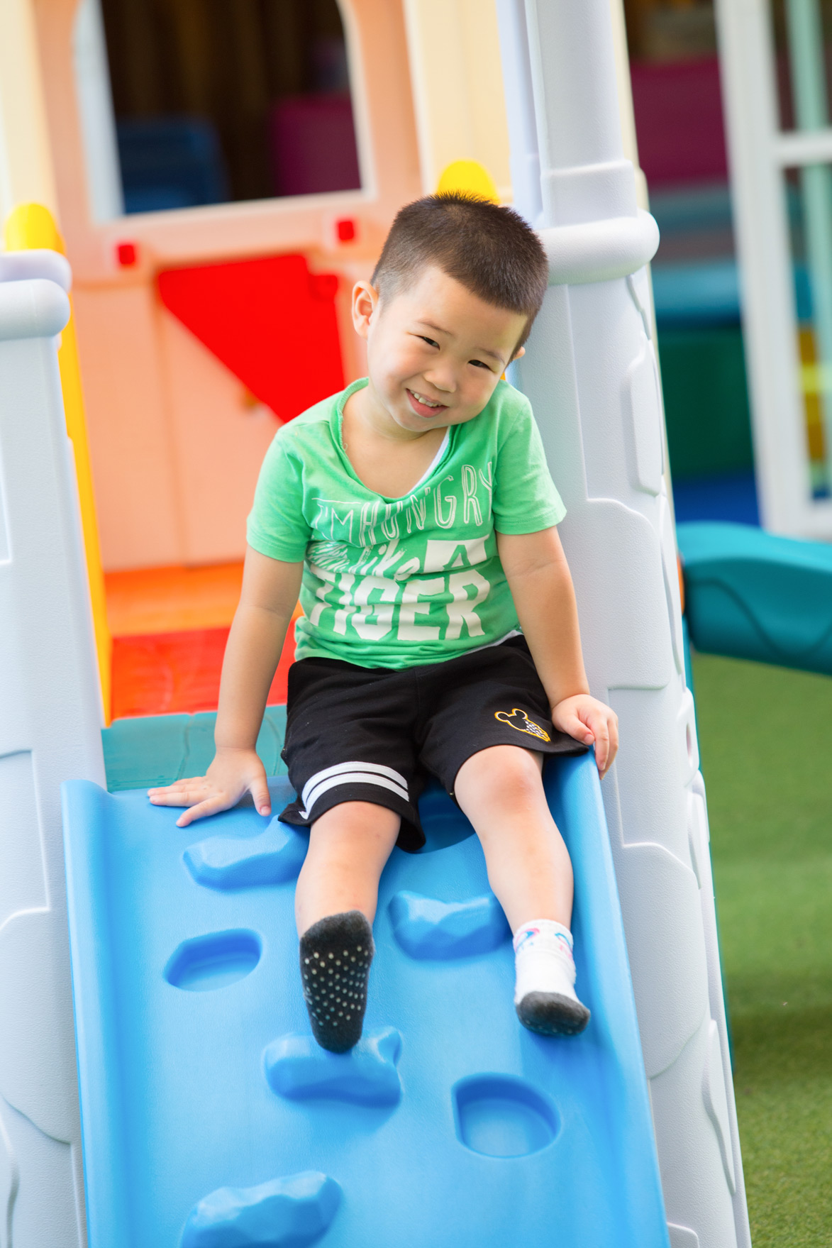 Teacher helping a nursery child down a blue slide